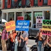 Protestas prieš NFT: NFT.NYC renginys su plakatais „Dievas nekenčia NFT“