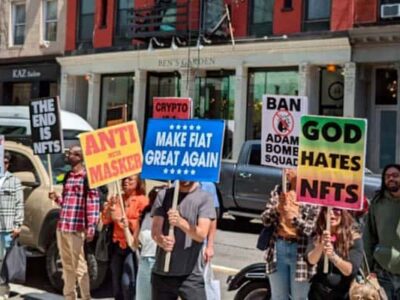 Manifestation anti-NFT : événement NFT.NYC avec affiches, "Dieu déteste NFT"